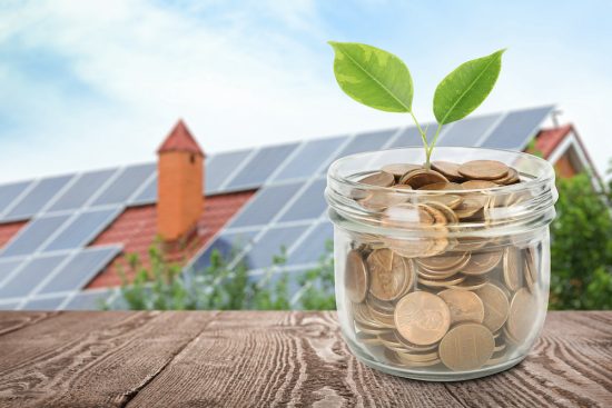 Háztető napelemekkel és távolabb egy befőttes üveg tele aprópénzel